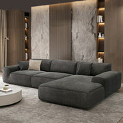 Gray sectional sofa in a modern living room with stone wall and bookshelves.